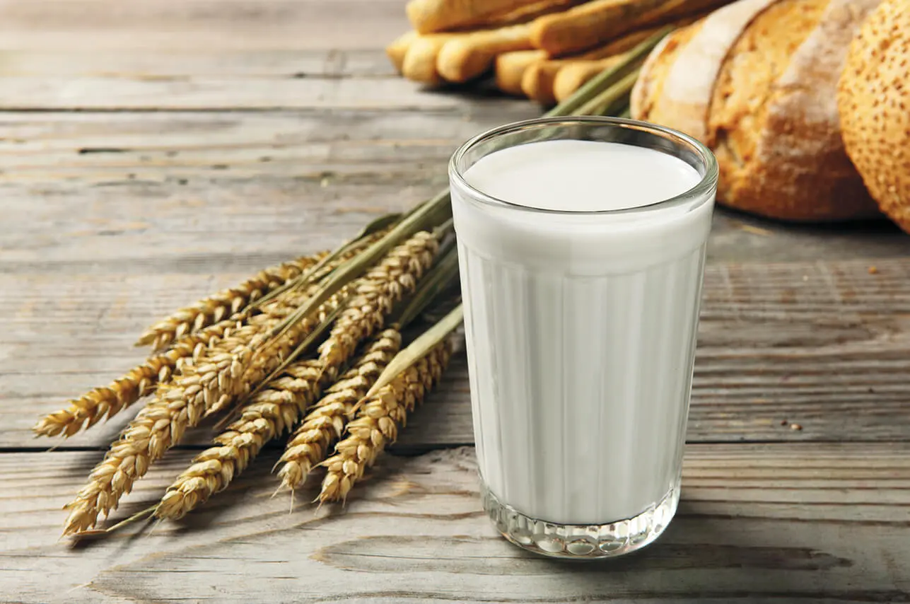Getreidehalme und ein Glas Milch, dahinter sieht man noch Gebäck in verschiedenen Variationen